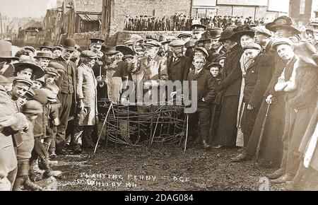 Una fotografia storica che mostra la cerimonia annuale 1911 di piantare il Penny Hedge o Horngarth nel fiume Esk a Whitby, North Yorkshire, Regno Unito. Al completamento della siepe l'uomo con il corno soffia 'su di voi' (uscire) sfidando la marea a distruggere la siepe penny entro tre maree, in linea con una leggenda locale. La consuetudine si svolge presso il seno di Abramo alla vigilia del giorno dell'Ascensione (40° giorno dopo la domenica di Pasqua), nel fango sulla riva orientale del fiume Esk . I magazzini in background non sono più e la grande folla tradizionale di spettatori da ogni scuola non più visita. Foto Stock