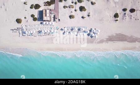 Vista aerea dall'alto del bar sulla spiaggia e del mare turchese, con ombrelloni e lettini in bella giornata estiva soleggiata. Foto Stock