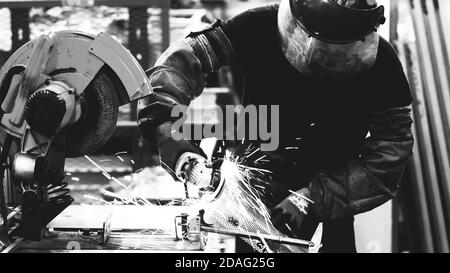 Lavoratori dell'industria pesante che tagliano acciaio con rettificatrice nella produzione industriale, bianco e nero Foto Stock