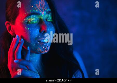 Ritratto di bella donna con trucco al neon. Vernice fluorescente a luce ultravioletta. Foto Stock