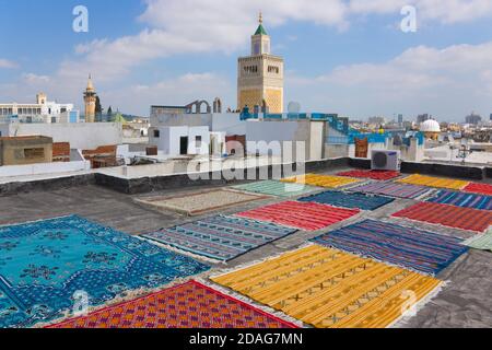 Tappeti essiccanti sul tetto nella vecchia medina, la Moschea di al-Zaytuna in lontananza, sito patrimonio dell'umanità dell'UNESCO, Tunisi, Tunisia Foto Stock