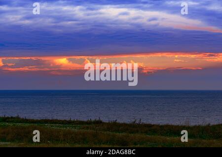 la sera, il sole tramonta sul mare e il crepuscolo si addensa, si forma una luminosa finestra colorata nel cielo Foto Stock