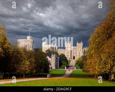 Il Castello di Windsor e il cielo oscuro, volando con il Royal Standard con la Regina Elisabetta in residenza, ammirarono la lunga passeggiata con gli escursionisti, in colore autunnale con spettacolari pozzi di luce solare e il cielo tempestoso scuro Windsor Berkshire UK Foto Stock