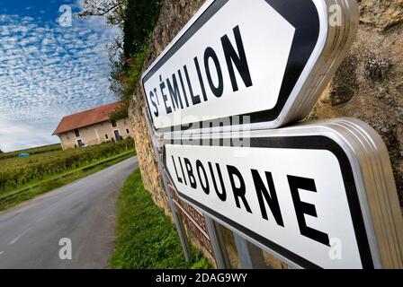 Cartello stradale St.Emilion/Libourne nel cuore dei vigneti che indicano St-Emilion e Libourne con cantina Chateau Angelus e vigneti dietro Pomerol Bordeaux France Foto Stock