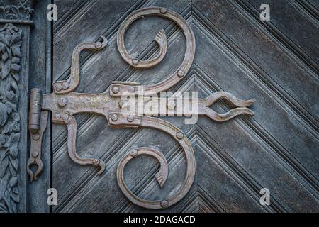 Primo piano su cerniere in ferro d'epoca in stile barocco su porta in legno con ornamenti a cornice. Cattedrale di Szczecin, Polonia Foto Stock