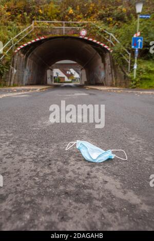 Una maschera abbandonata di fronte ad un tunnel che simboleggia La pandemia di Corona o Covid-19 Foto Stock