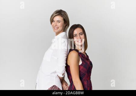 Amici felici che si divertono su sfondo bianco. Due belle giovani donne Foto Stock