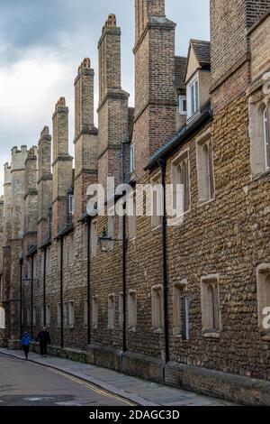 una fila di storici cottage a schiera in pietra nella città universitaria di cambridge con due persone che camminano lungo il marciapiede. Foto Stock