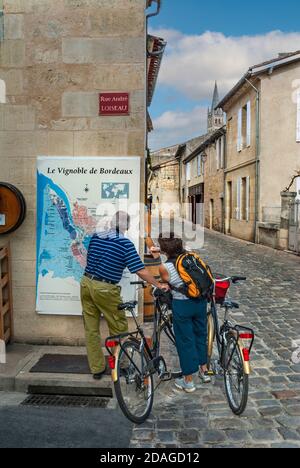 SAINT EMILION MAPPA Cicloturismo coppia con noleggio biciclette fermarsi a guardare la mappa della regione vinicola di Bordeaux nel centro di St. Emilion Bordeaux Francia Foto Stock