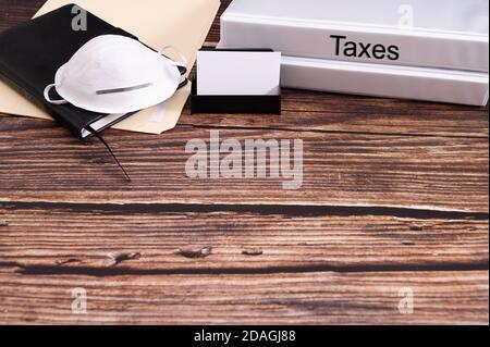 Concetto fiscale durante il coronavirus con cartella ufficio con iscrizione tasse sulla scrivania in legno. Spazio per il testo. Foto Stock
