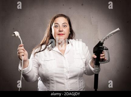 donna che sorregge un ugello della pompa di alimentazione e un cavo elettrico Foto Stock