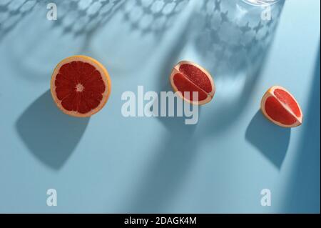 Sfondo creativo con fette di pompelmo rosso e ombre dure. Stile minimalista. Orientamento orizzontale con spazio per il testo. Foto Stock