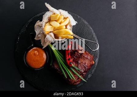 costolette di manzo alla griglia con salsa e patate Foto Stock