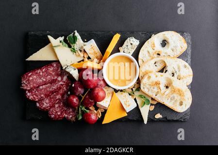 formaggi e tagli di carne su fondo nero Foto Stock