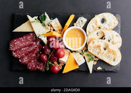 formaggi e tagli di carne su fondo nero Foto Stock