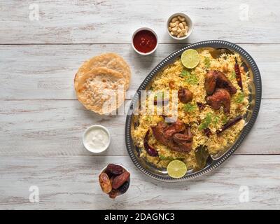 Pollo Mandi con datteri su un tavolo bianco. Cucina araba. Vista dall'alto. Foto Stock