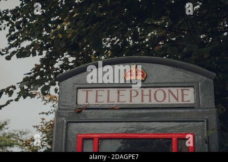 Frome, UK - 7 ottobre 2020: Vista ad angolo basso della scatola telefonica rossa e grigia contro gli alberi. Grigio con caselle rosse sono installate aree di naturale e architettu Foto Stock