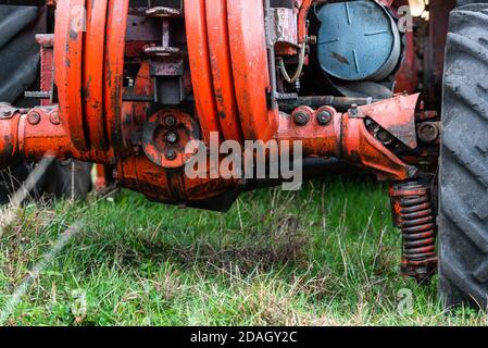 Primo piano dello sprint ammortizzamento sugli pneumatici anteriori del trattore raro unico rosso arrugginito russo veicolo agricoltura autunno all'aperto Foto Stock