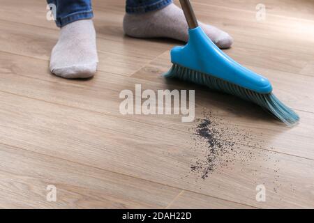 L'uomo spazza i detriti in una paletta blu con una spazzola. Foto Stock