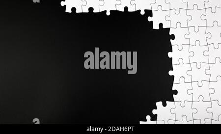 Pezzi di puzzle bianco incompiuto su sfondo nero Foto Stock