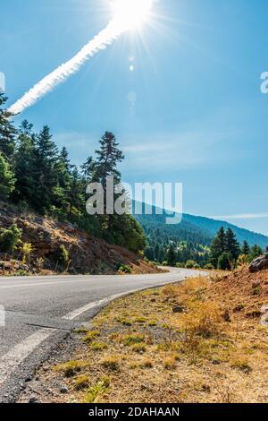 Vista sulla strada delle foreste del monte mainalo in una giornata di sole con un cielo blu. Foto Stock