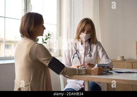 Medico la misura della pressione del sangue dei suoi pazienti in stato di gravidanza Foto Stock