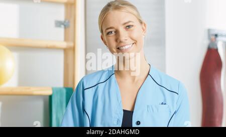 Ritratto di bello giovane assistente di fisioterapia dell'infermiera professionista sorride charmingly. Foto Stock