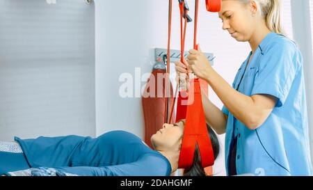 Fisioterapista assiste le donne con trauma, sottoponendo a fisioterapia Riabilitativa su un sistema di corda a sospensione speciale. Alleviare il dolore alla schiena Foto Stock