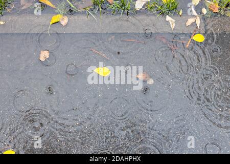 vista dall'alto del puddle sul sentiero asfaltato in autunno pioggia Foto Stock