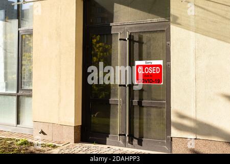 Primo piano su un cartello rosso chiuso nella finestra di Un negozio che visualizza il messaggio chiuso a causa di Covid-19 Foto Stock