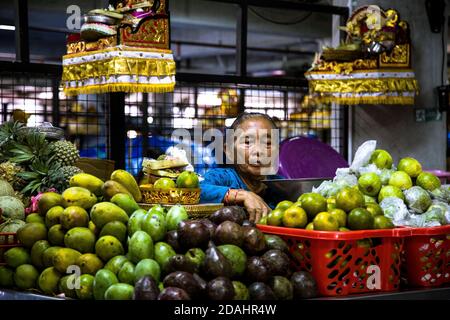 Denpasar, Bali, Indonesia - 8 AGOSTO 2019 : Ritratto di una donna che vende frutta esotica al mercato locale coperto. Foto Stock