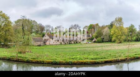 Cottage tradizionali e attraenti in pietra a schiera Cotswold in Arlington Row by Il fiume Coln nel villaggio di Bibury nel Gloucestersire Cotswolds Foto Stock