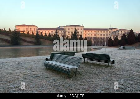 Tre panchine si trovano nel Parco sull'erba gelata Sullo sfondo di una casa di cura - il Palazzolo-Don Istituto Gnocchi del nuovo portello Foto Stock