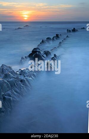 Vista delle sporgenze rocciose al tramonto a Welcombe Mouth Spiaggia sul confine tra Devon e Cornovaglia Foto Stock