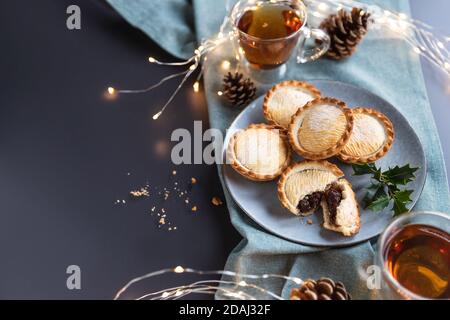 mince torte su un piatto servito con tè nero shot da sopra con spazio copia. Una torta mince è una tradizionale torta dolce natalizia, ripiena di frutta secca e spezie. Foto Stock