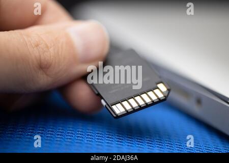 Installazione di una scheda SD in un computer portatile. Primo piano. Concetto di protezione delle informazioni e di sicurezza digitale Foto Stock