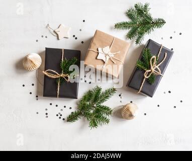 Piatto di regali di Natale imballato sostenibile. Confezione natalizia in colori naturali e neri su sfondo bianco. Vista dall'alto. Foto Stock