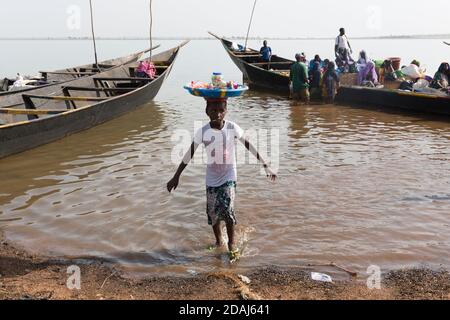 Selingue, Mali, 25 aprile 2015; Cariere villaggio sul lago di diga è un villaggio di pescatori. Una giovane ragazza che vende dolci ai passeggeri sulle barche che li ferry alle altre città sul lago. Foto Stock