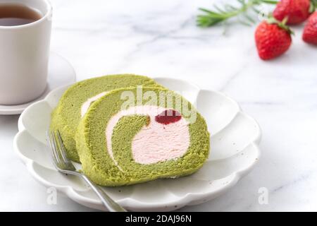 Delizioso Matcha Swiss Roll Cake fette con crema alla fragola su sfondo bianco, primo piano. Foto Stock