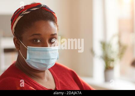 Primo piano di giovane donna africana che indossa maschera protettiva guardando fotocamera Foto Stock