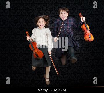 due ragazze con violini che saltano su uno sfondo vintage Foto Stock