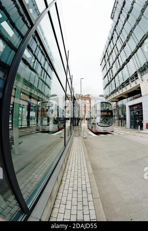 Lo Shudehill Interchange nel centro di Manchester offre una stazione degli autobus e una fermata della metropolitana (tram). Un autobus e gli edifici si riflettono nelle sue finestre. Foto Stock