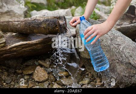 Prendendo acqua di sorgente da una sorgente di montagna. Riempimento acqua in bottiglia in plastica, fonte di acqua pura naturale. Foto Stock