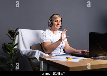 Donne anziane in cuffia che parlano tramite videochiamata a casa utilizzando un computer. Foto con spazio laterale vuoto. Concetto online senior e concetto pandemico. Foto Stock