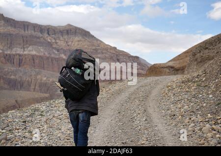 KAGBENI, MUSTANG / NEPAL - 21 agosto 2014: Unidentified facchino assunto che sono assunti per trasportare uno zaino di turisti, va sulla strada per Himalaya Foto Stock