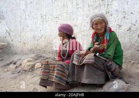 Due nonna molto vecchia in costumi tradizionali seduti vicino al muro bianco sulla strada. Foto Stock