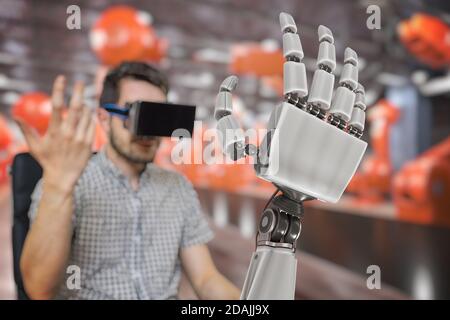 L'uomo con la cuffia controlla il braccio robotico con la mano. Rappresentazione 3D della mano robotica. Foto Stock