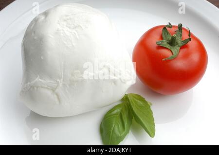 Un piatto di mozzarella di bufala della Campania spola il pomodoro e il basilico fresco su un piatto bianco Foto Stock