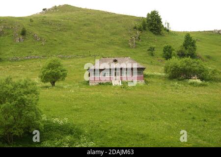 Contea di Brasov, Romania. Piccola casa tradizionale in montagna, con un tetto di tegole in legno. Foto Stock