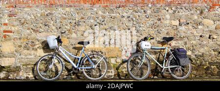 Due biciclette appoggiate contro un muro a Bosham. Foto Stock